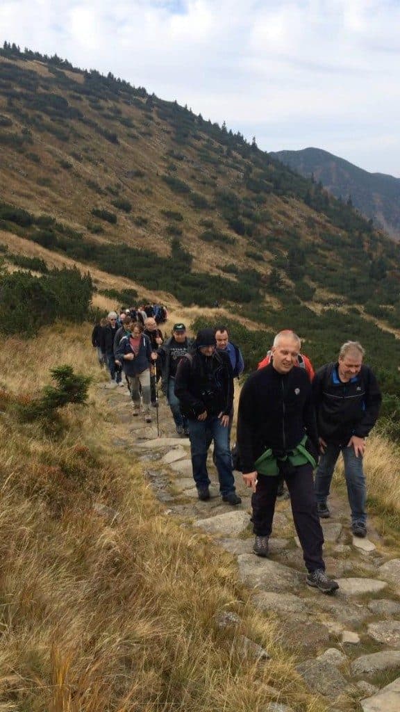 Skupina stoupá po kamenité horské stezce mezi travou a kosodřevinou